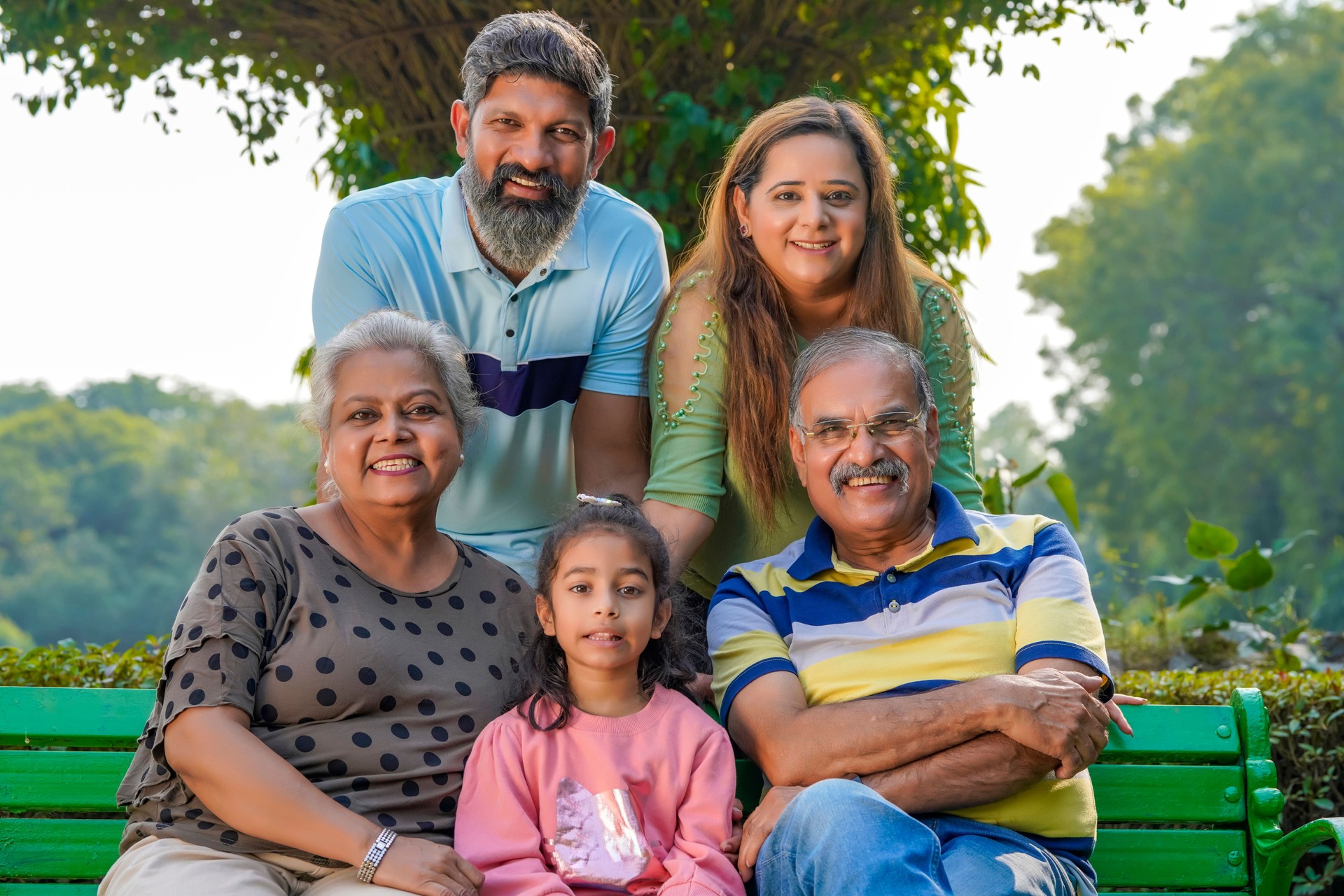 Happy indian or asian family sitting at park.