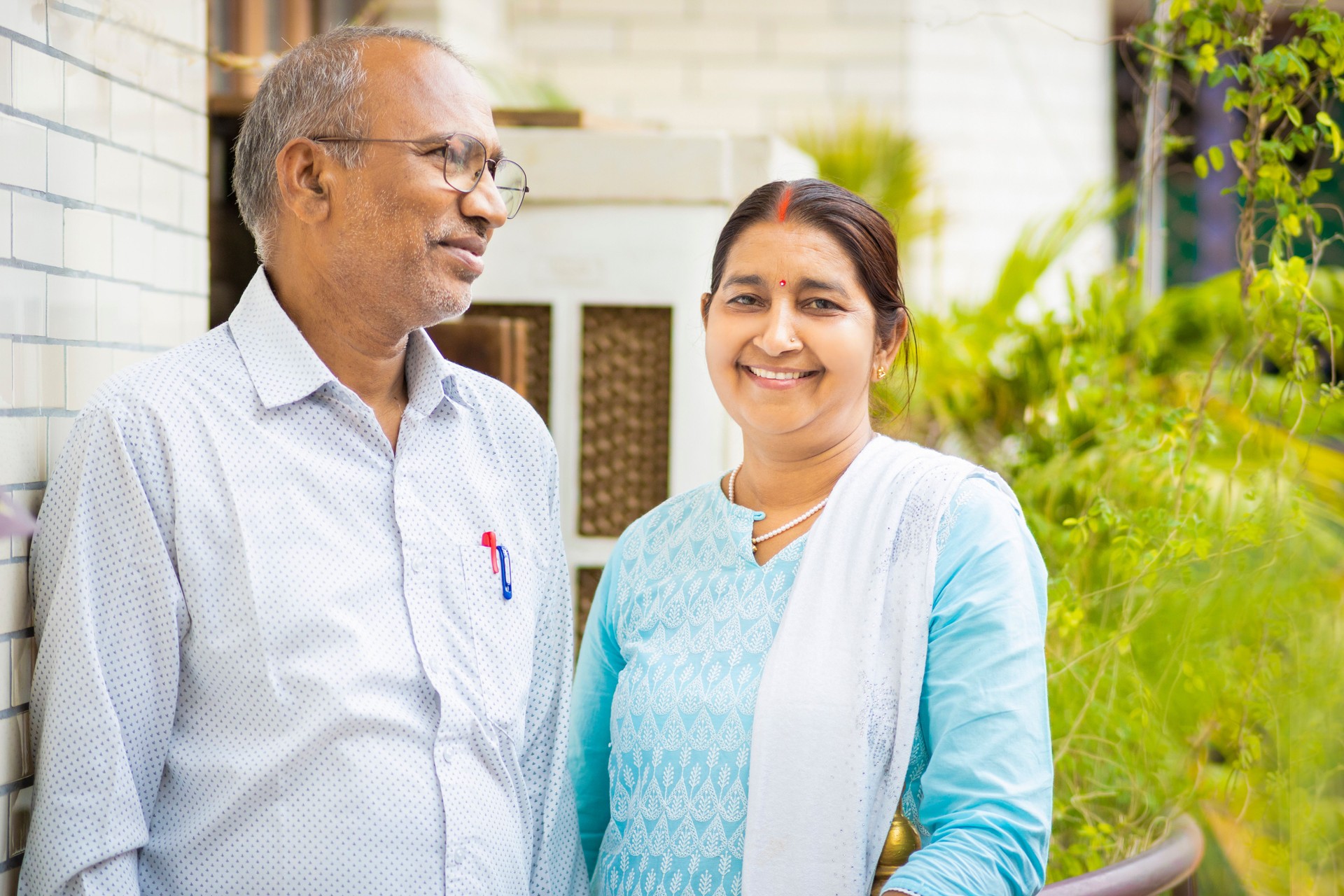 Happy indian mid adult couple talking and spending time together on their house balcony.